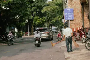 Local street scene in Thao Dien with motorbikes and a street sweeper, pointing toward Hanoi Highway