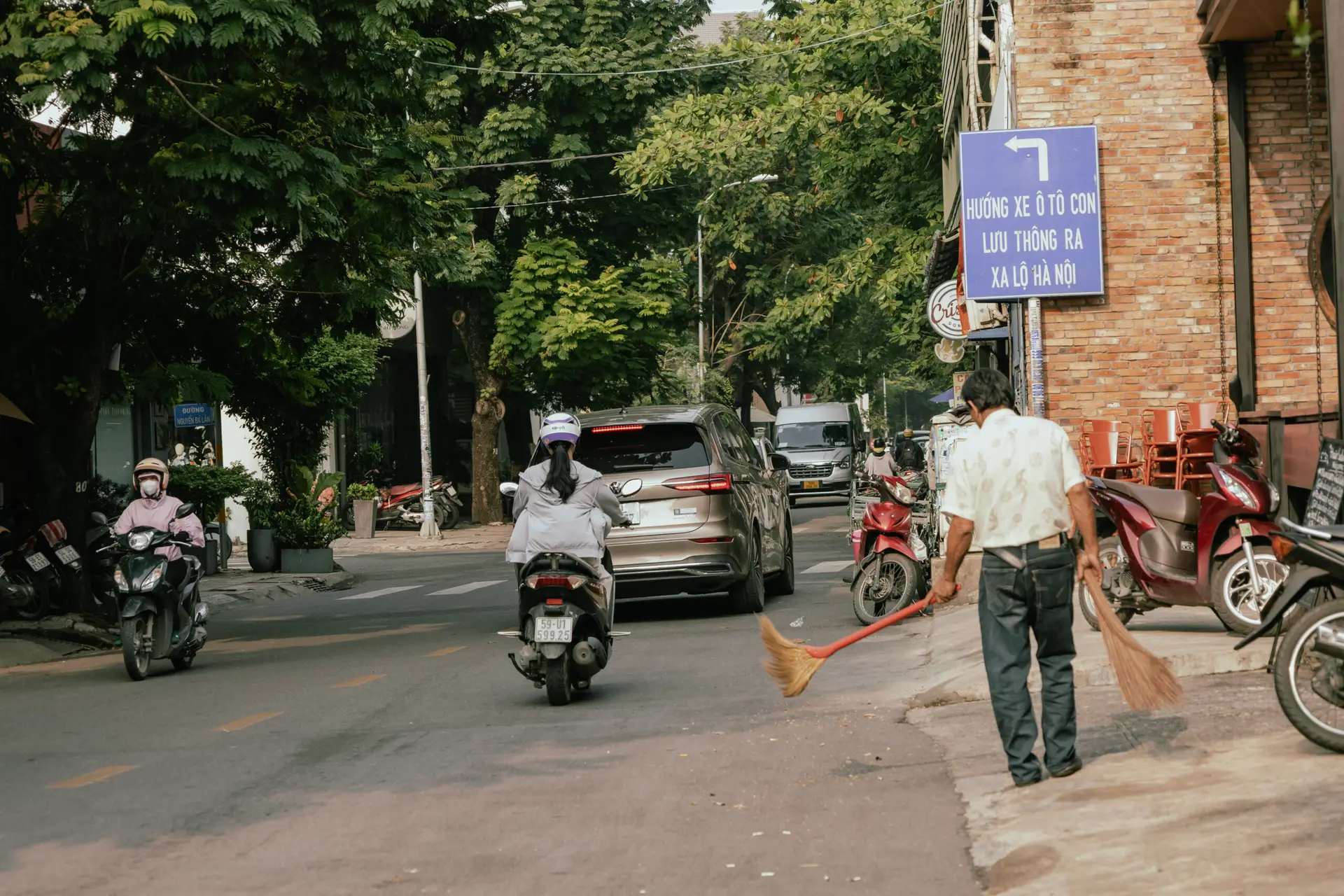 Local street scene in Thao Dien with motorbikes and a street sweeper, pointing toward Hanoi Highway