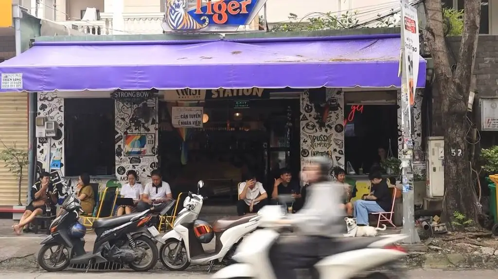 Motorbikes passing an open-front café with a purple awning