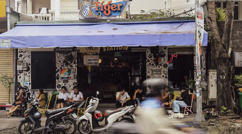 People sitting outside a neighbourhood café beneath a purple awning